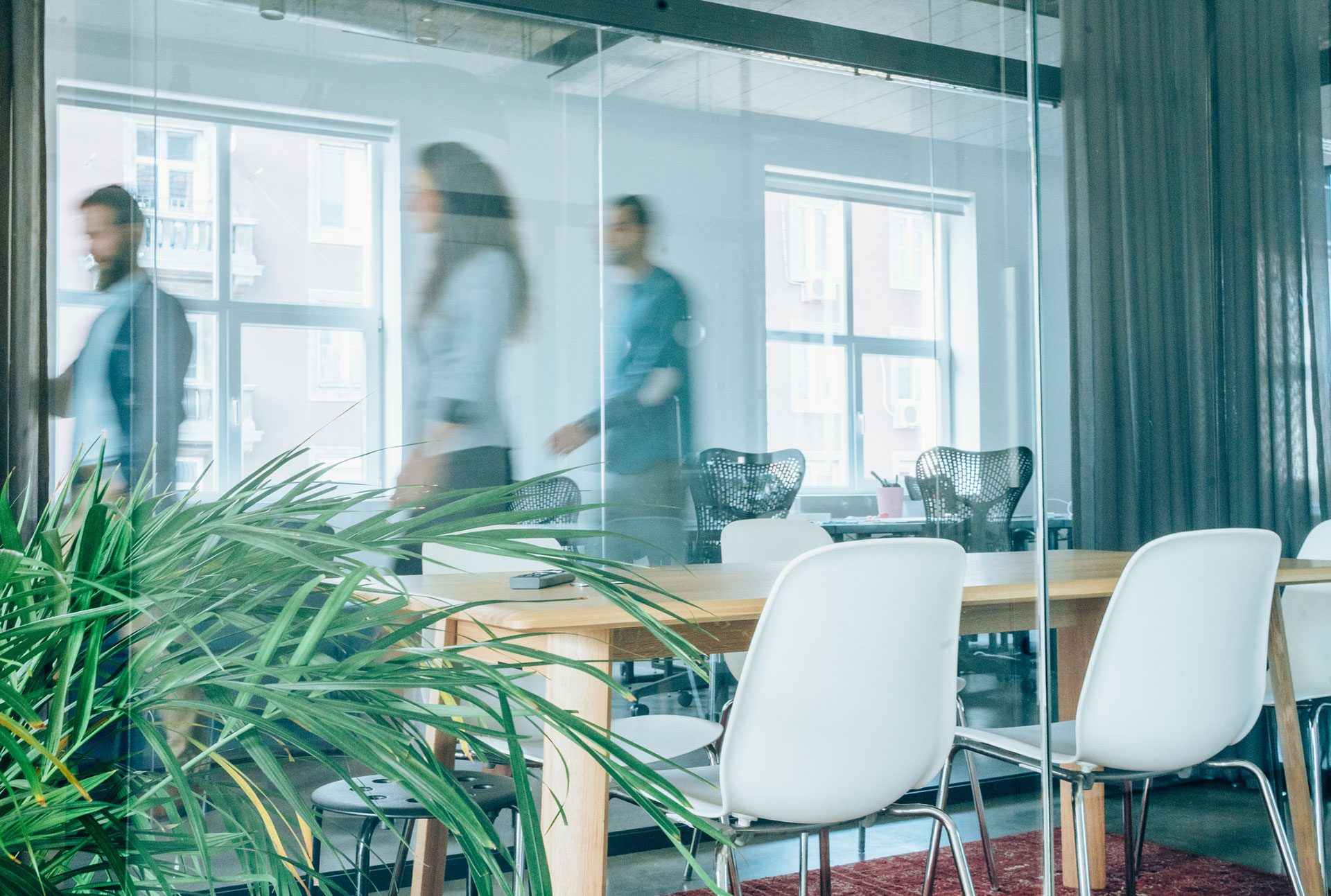 People walking around an office behind a desk with chairs